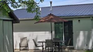 A patio with a table and chairs, a brown umbrella, and a metal roof. - Quite and cozy / Boat ramp nearby.  (Minster)