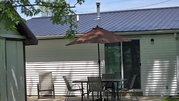 A patio with a table and chairs, a brown umbrella, and a metal roof. - Quite and cozy / Boat ramp nearby.  (Minster)