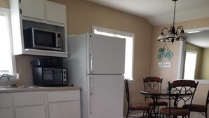 A kitchen with white cabinets, a microwave, a toaster, and a refrigerator. There is a dining table with chairs and a chandelier. - Quite and cozy / Boat ramp nearby.  (Minster)
