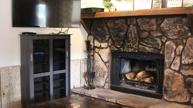 Een woonkamer met een stenen openhaard, een flatscreen televisie aan de muur en een donkerhouten salontafel.