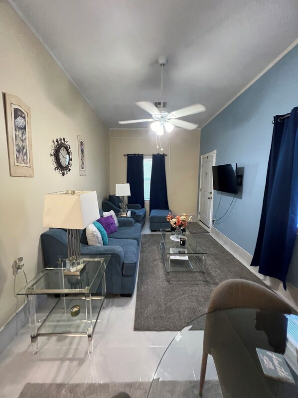 A living room with a sofa, coffee table, and a ceiling fan.
