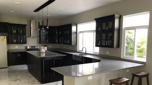 A modern kitchen with dark cabinets, a large island, and a window providing natural light.