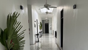 A hallway with a marble floor, a ceiling fan, and a potted plant on a console table.