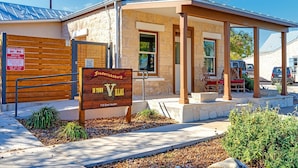 Un edificio con fachada de piedra, un porche cubierto y un cartel que indica 'Fredericksburg in Town Villas' en el 115 de la calle East Austin.