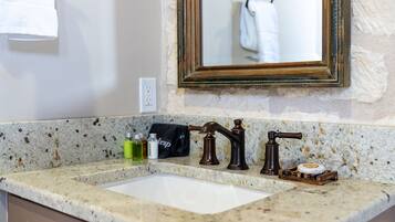 A bathroom with a granite countertop, a white sink, and a mirror with a wooden frame.