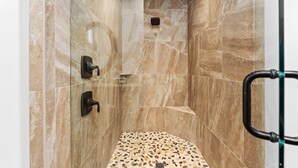 Douche met betegelde vloer en een douchekop aan de muur.
