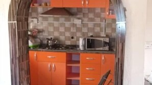 Keittiössä on oranssit kaapit, laatoitettu välitila ja geometrisesti kuvioitu lattia.