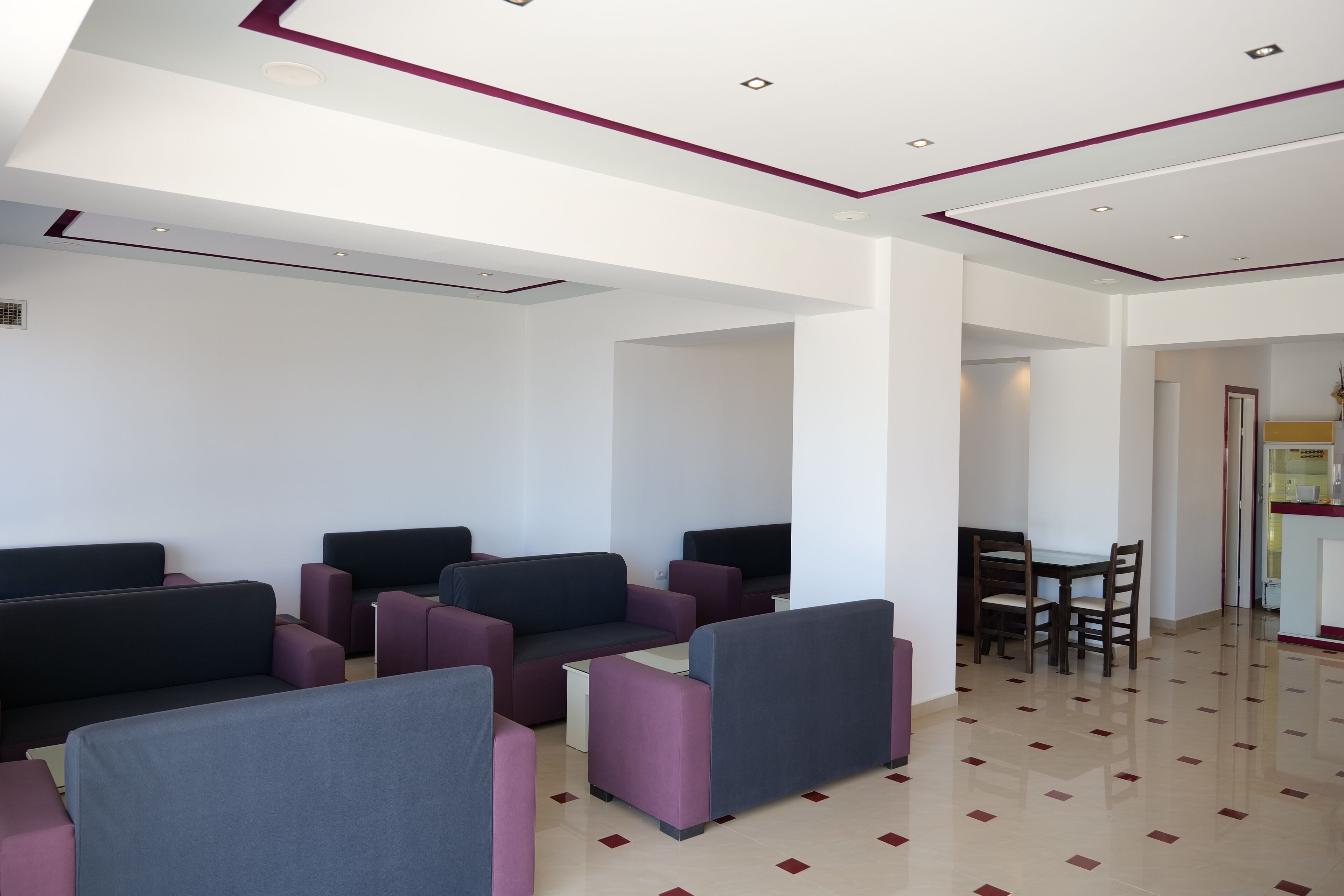 A modern waiting area with multiple seating options, a dining table, and a clean, tiled floor.