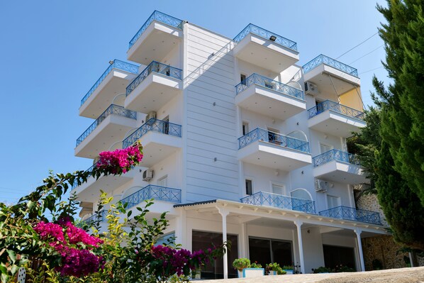 A multi-story hotel with balconies, a covered entrance, and surrounding greenery.