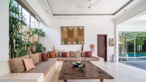 A modern living room with a large sectional sofa, a wooden coffee table, and a large abstract painting on the wall. - Elegant Private Villa, 3 BR, Seminyak With Staff (Keroboken Kelod)