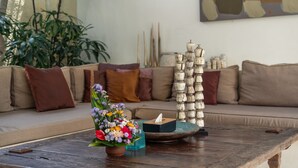 A living room with a sofa, a coffee table, a vase with flowers, and a decorative stack of vases. - Elegant Private Villa, 3 BR, Seminyak With Staff (Keroboken Kelod)