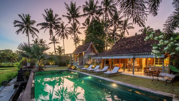 A poolside area with lounge chairs and a building with a tiled roof.