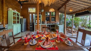 A wooden dining area with a table set for a meal, surrounded by chairs.