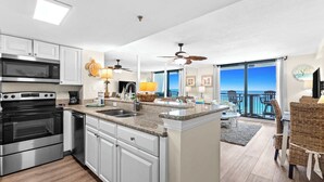 A modern kitchen with a central island, a dining area with a view, and a balcony with outdoor seating.