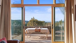 A room with a large sliding glass door leading to an outdoor dining area with a table set for two.