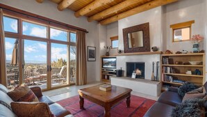 A spacious living room with a large window, a fireplace, a television, and a cozy seating area.