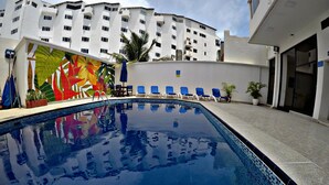 A swimming pool with blue tiles, surrounded by lounge chairs and a colorful mural. - SEA VIEW APARTMENT CLOSE TO THE BEACH (San Andrés y Providencia)