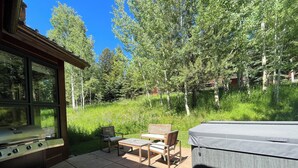 A patio with a grill, two wooden chairs, and a hot tub.