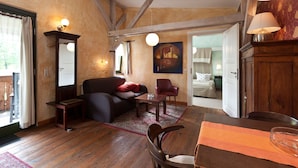 Une pièce chaleureuse avec un plancher en bois, un canapé, une table à manger avec des chaises, un miroir et un tableau accroché au mur.