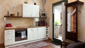 Une cuisine de taille réduite avec des meubles blancs, un four à micro-ondes et une bouilloire rouge.