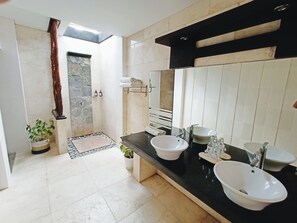 Een aparte badkuip en douche, een diep bad, een regendouche
