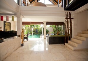 Un vestíbulo amplio con piscina, escalera y recepción.