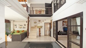 A spacious interior with a staircase leading to an upper level, a seating area with cushions, a large window, and a flat-screen TV. - Harmony Villa Dua (Kerobokan)