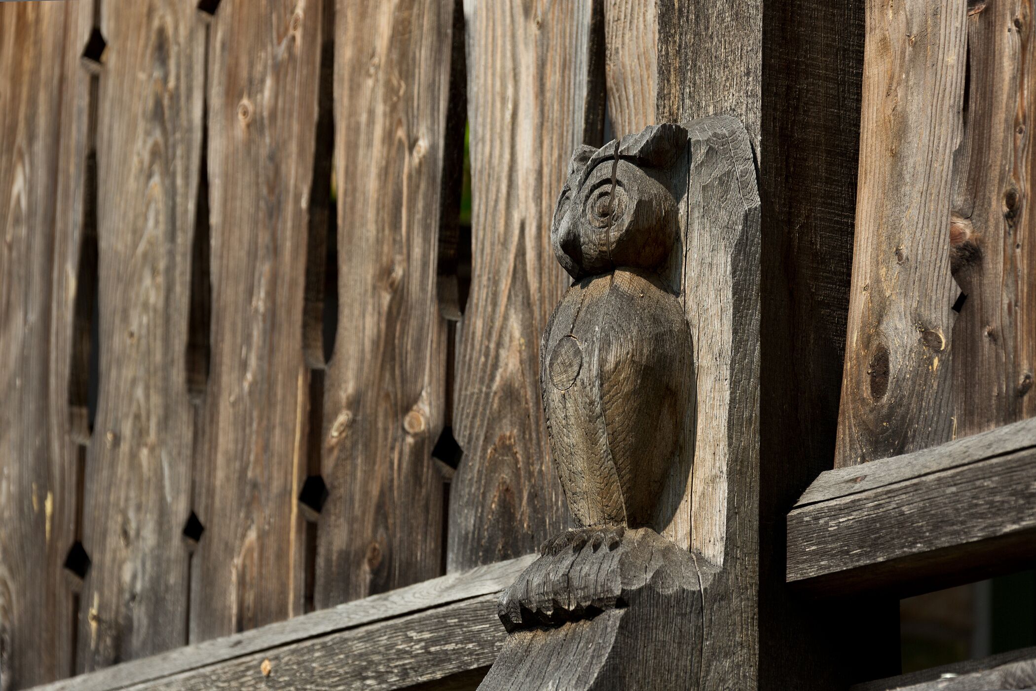 A wooden fence with a carved owl figure.