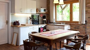 A kitchen with white cabinets, a wooden table, and a window with curtains. - Storage N ° 1 - Lily (Waren (Müritz))