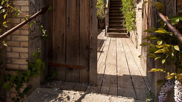 A wooden door with intricate carvings, a stone staircase, and a brick wall. - Storage N ° 1 - Lily (Waren (Müritz))