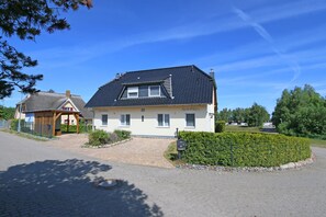A two-story house with a dark roof, a small porch, and a well-maintained garden.