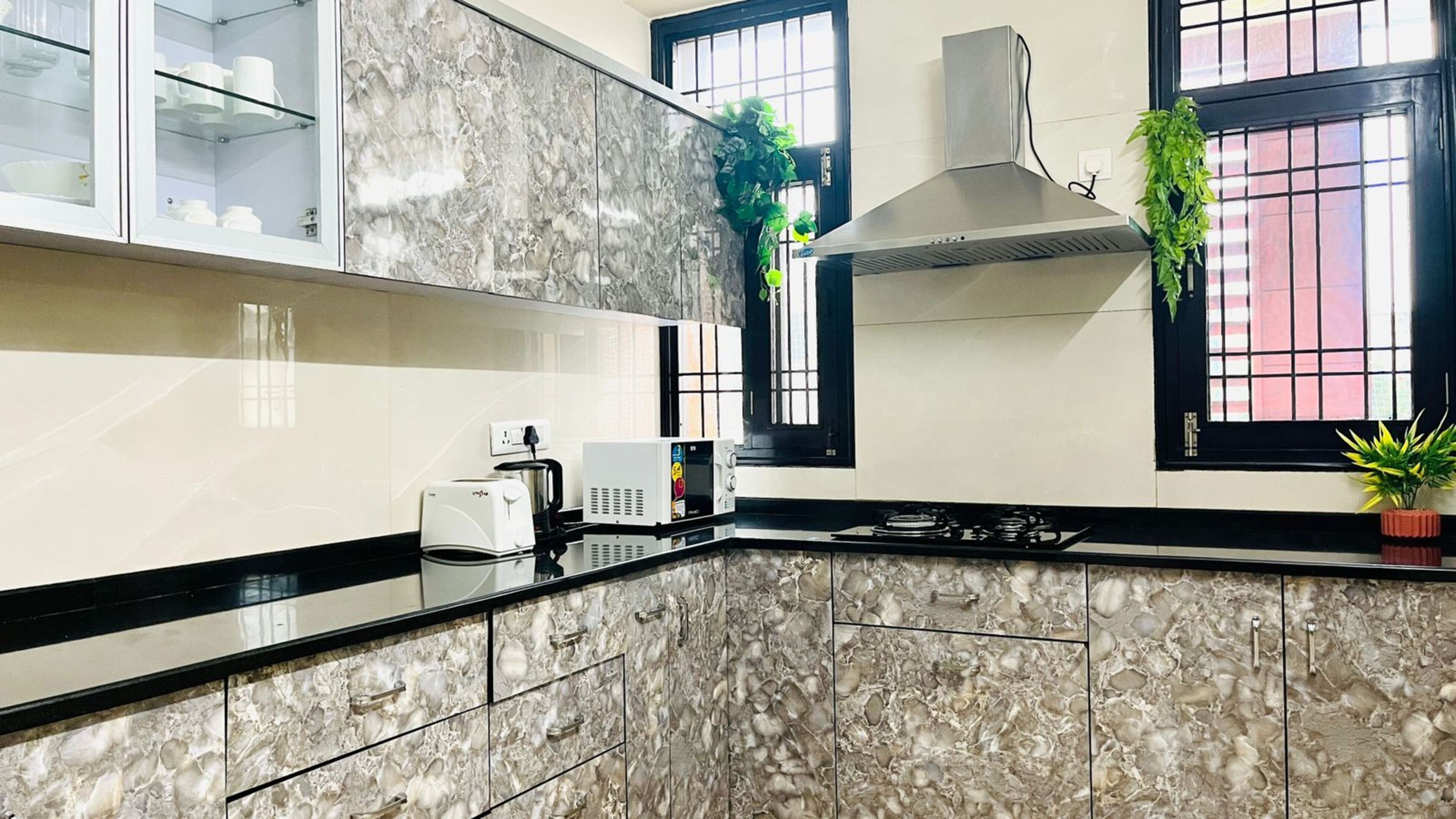 Una cocina moderna con encimeras de mármol, horno empotrado, estufa y campana extractora.