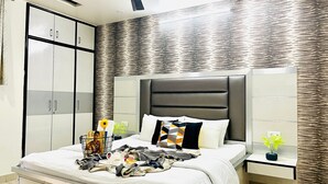 Une chambre à coucher moderne avec un grand lit, une armoire et une table de chevet agrémentée d’une plante.