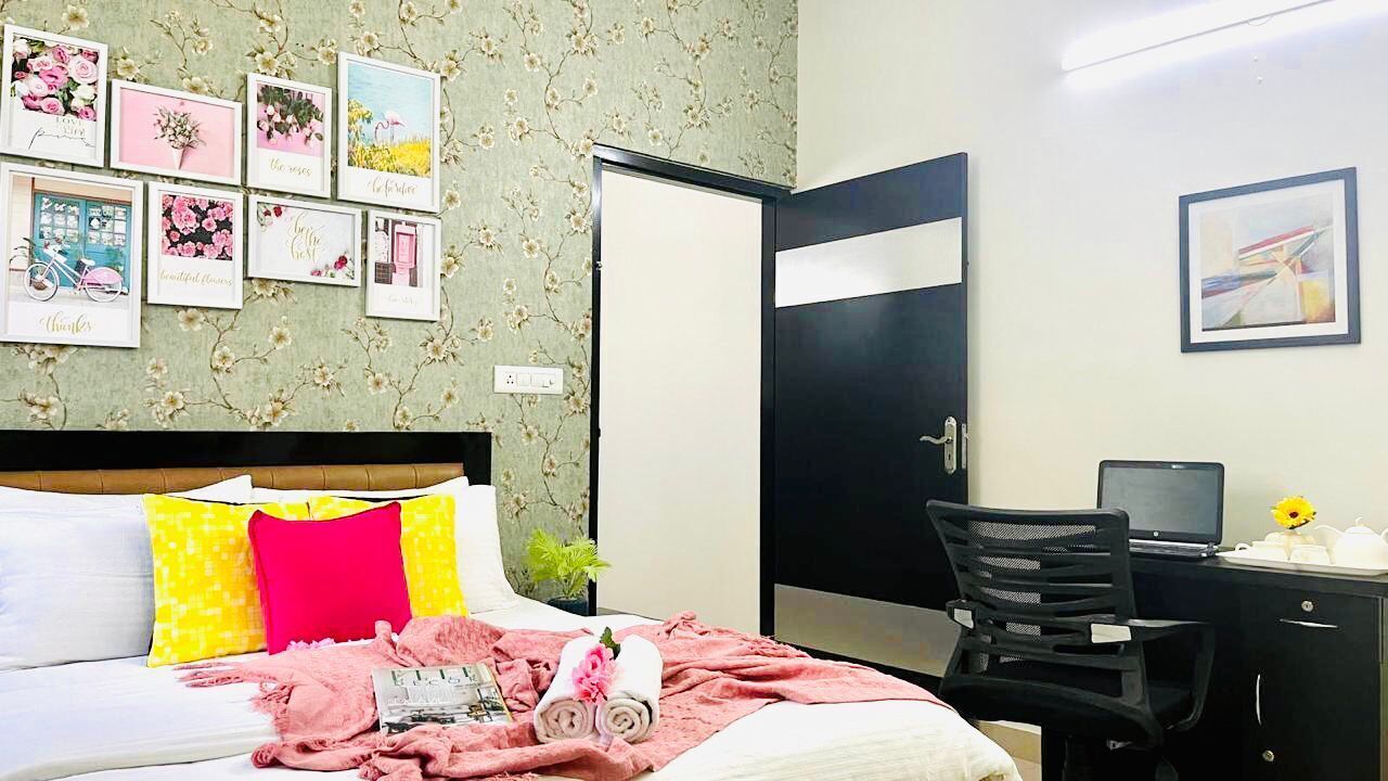 A hotel room with a bed, a desk, a chair, and a door.