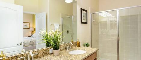 A bathroom with two sinks, a shower, and a large mirror.