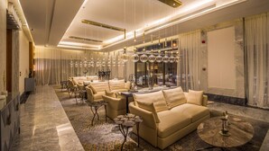 A modern hotel lobby with a sofa set, a coffee table, and a chandelier.