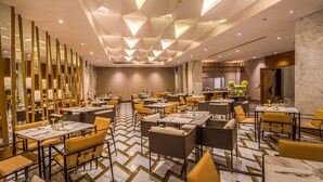 A modern dining area with tables and chairs, a patterned floor, and a geometric ceiling design.