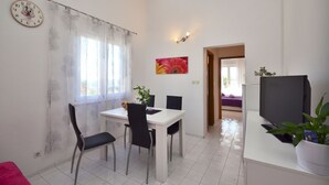 A dining area with a table, chairs, a clock, and a painting. - Laidback Apartments (Orebic)