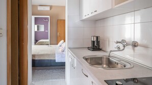A modern kitchen with a stainless steel sink, white cabinets, and a coffee machine. - Laidback Apartments (Orebic)