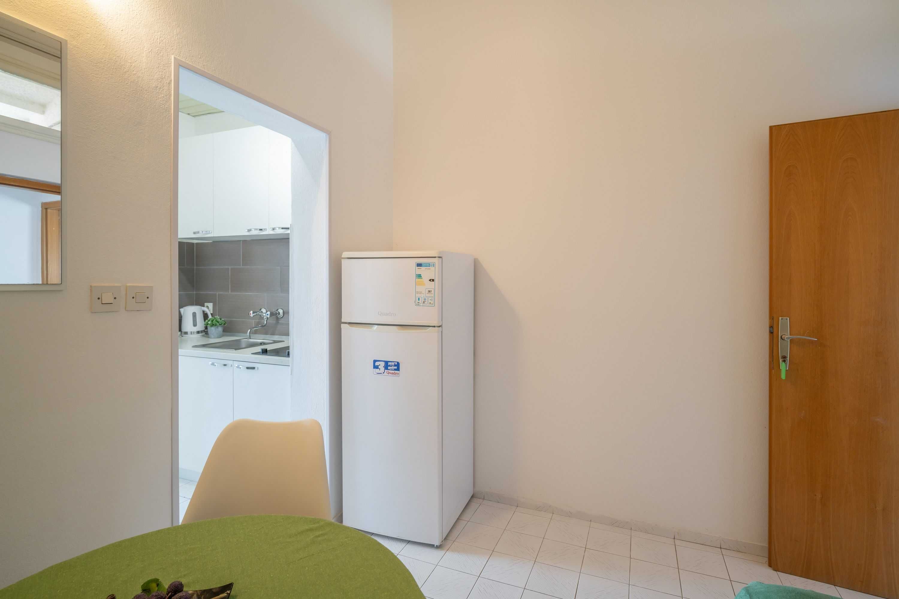 A compact kitchen with a refrigerator, a sink, and a dining area with a table.
