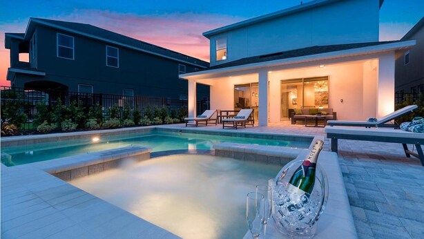 A modern house with a swimming pool, lounge chairs, and a bottle of champagne. - Ultimate 5 Star Villa with Private Pool on Encore Resort at Reunion, Orlando Villa 4363 (Orlando)