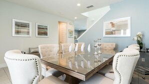 A dining area with a glass table, six upholstered chairs, and a staircase leading to another room. - Ultimate 5 Star Villa with Private Pool on Encore Resort at Reunion, Orlando Villa 4365 (Orlando)