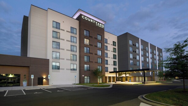 Hotel Courtyard by Marriott con diseño moderno, que presenta fachada de ladrillo, múltiples ventanas y una entrada bien iluminada.