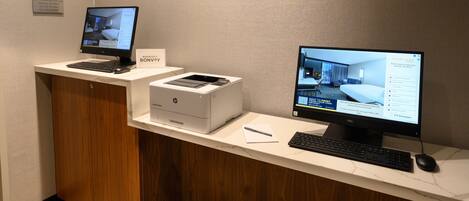 A reception desk with two monitors, a printer, and a keyboard.