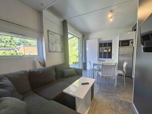 A compact living space with a sofa, a small table, a kitchenette, and a dining area. - comfortable mobile home on the lake with whirlpool (WA101) (Wackersdorf)