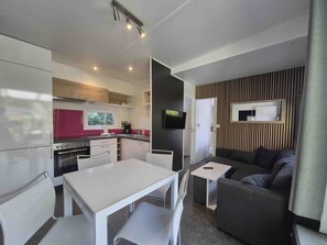 A compact living space with a kitchenette, dining area, and a seating area with a sofa and a small table. - comfortable mobile home on the lake with whirlpool (WA101) (Wackersdorf)