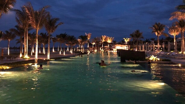A nighttime swimming pool area with palm trees and illuminated lights. - This is an apartment of 5* Alma resort at Bai Dai beach in Khanh Hoa (Nha Trang) (Cam Lam)