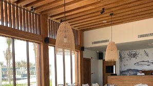A spacious dining area with wooden furniture, large windows, and a tiled floor. - This is an apartment of 5* Alma resort at Bai Dai beach in Khanh Hoa (Nha Trang) (Cam Lam)