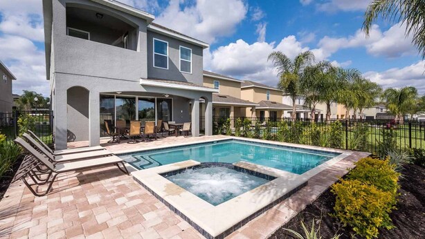 A two-story house with a swimming pool, patio with chairs, and a hot tub. - Luxury Contemporary Style Villa on Encore Resort at Reunion, Orlando Villa 4385 (Orlando)