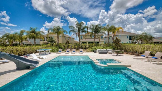 A swimming pool with lounge chairs and a slide, surrounded by palm trees and buildings. - Ultimate 5 Star Villa with Private Pool on Encore Resort at Reunion, Orlando Villa 4391 (Orlando)
